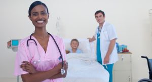 Smiling Indian nurse with doctor and patient in the background